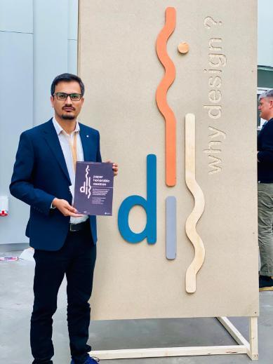 A man with black hair, brown skin, black moustache and beard dark glasses wearing a blue suit and light blue shirt. He is holding an 'honourable paper award' certificate from 2024 ACM SIGCHI Conference on Designing Interactive Systems.